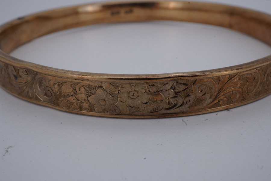 A gold bangle, engraved with scrolled decoration, inner circumference approximately 21.5cm, stamped 9CT, gross weight approximately 10 grams